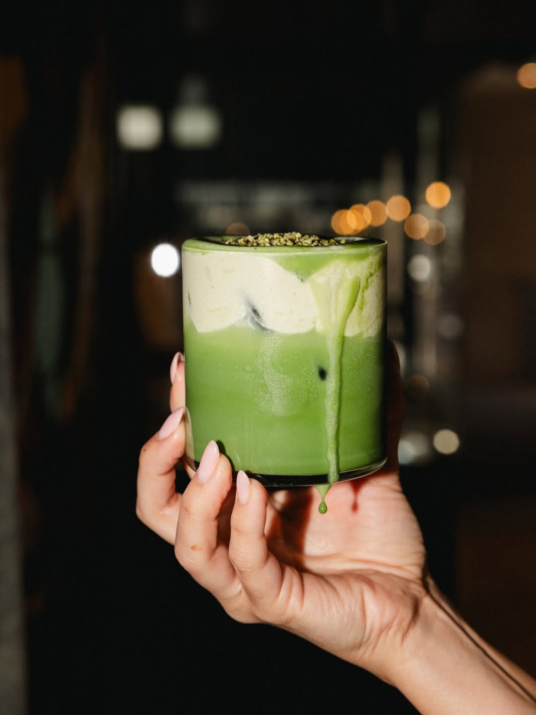 Iced matcha topped with cream held against the evening light